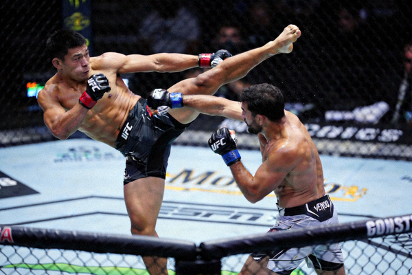 UFC羽量级比赛，两位选手在笼中进行高扫踢与拳法组合的攻防